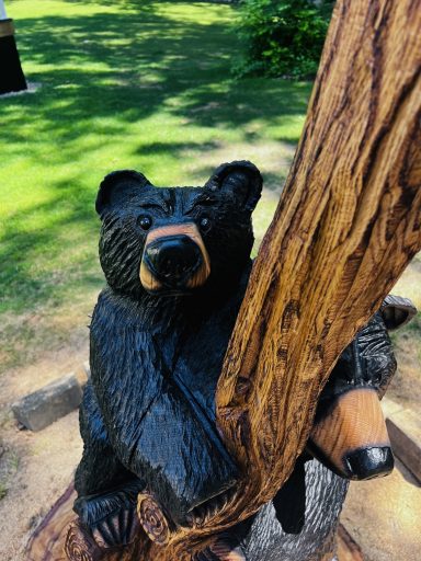 Close-up of the cub climbing, with momma peeking out behind. On-site oak stump carving, Pascoag, RI. Cub climbing with momma bear peeking out behind, close-up
