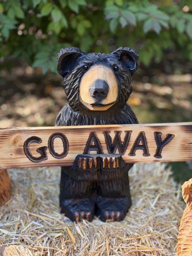 Cute 16" bear holding a reversible "Welcome / Go Away" sign. Pine log. Bear holding reversible Welcome Go Away sign
